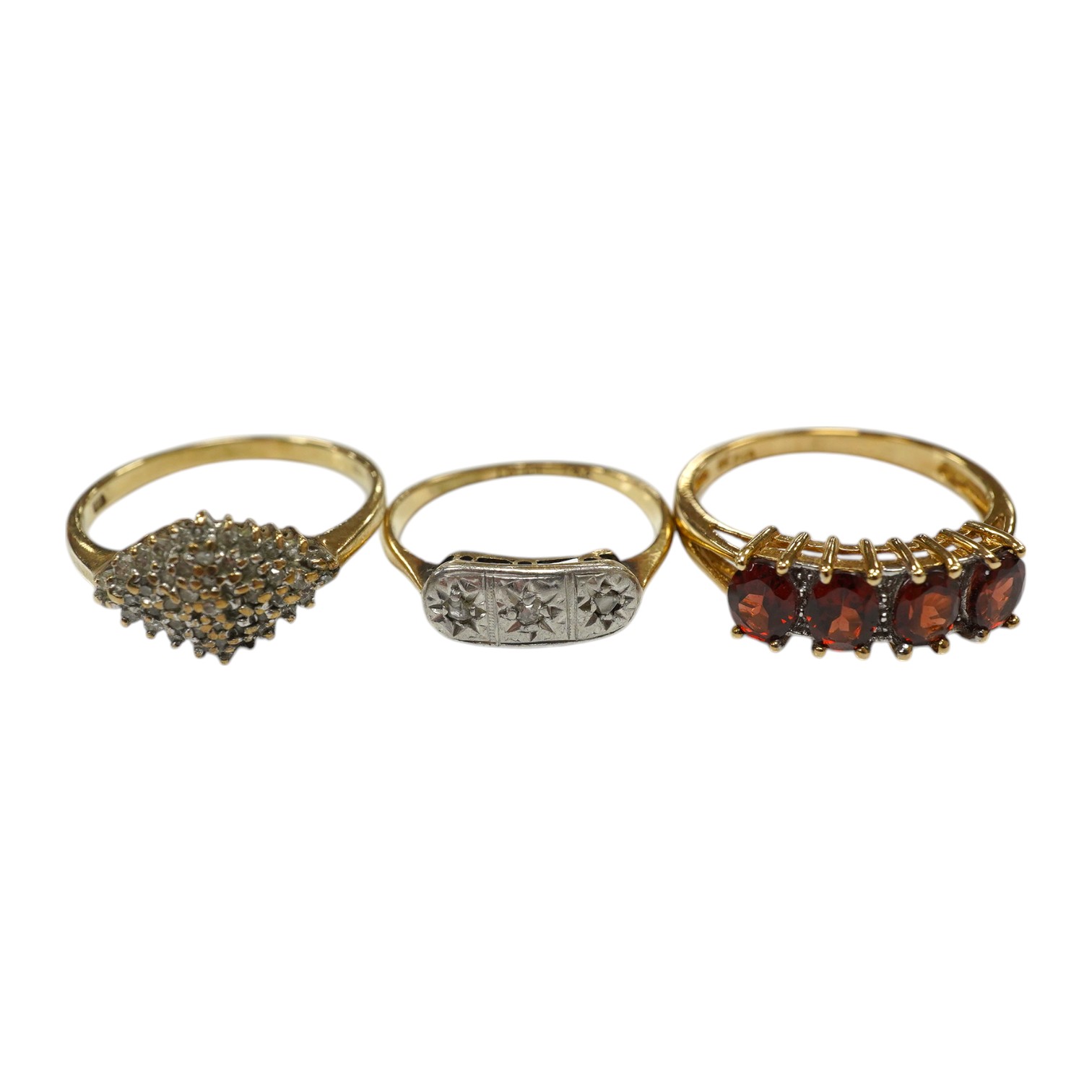 Three assorted 9ct and gem set rings, including three stone diamond, diamond chip cluster and garnet and diamond half hoop, gross weight 6.3 grams. Condition - fair